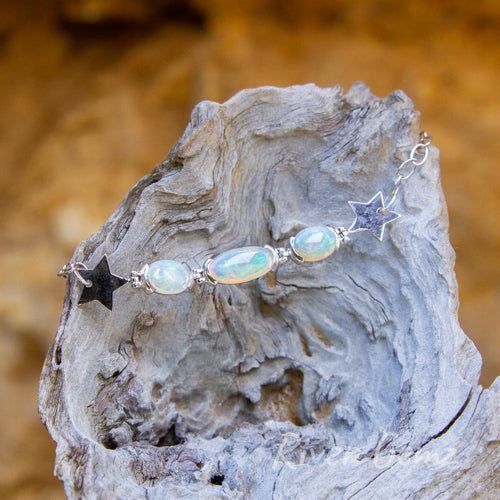 Similar photo to the first but taken a little further away. Three opals with good polish with large silver stars to start and end the sequence of 3 opals featured.