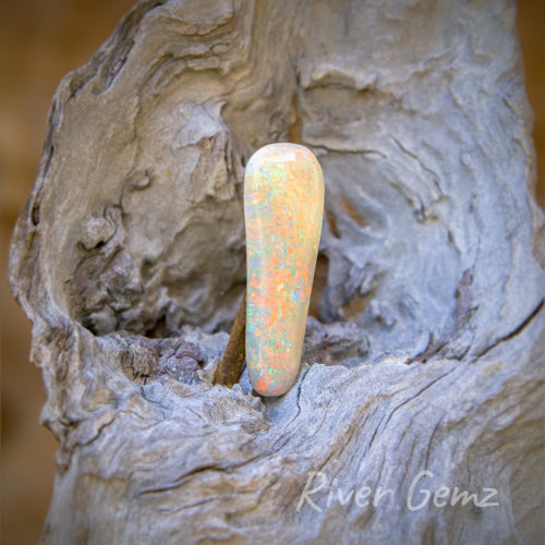 Long free-form cut light opal with orange, blue and green flecks of colour throughout.