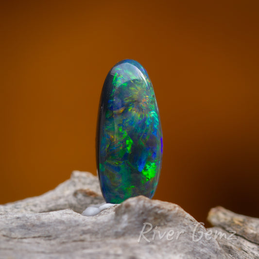 Large spheres of colour in dark opal standing up on light grey grained wood.