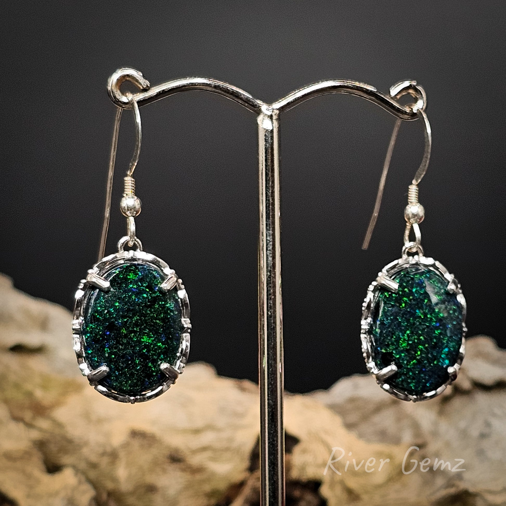 Large silver hooks shown with oval shaped dark opals with speckles of green.