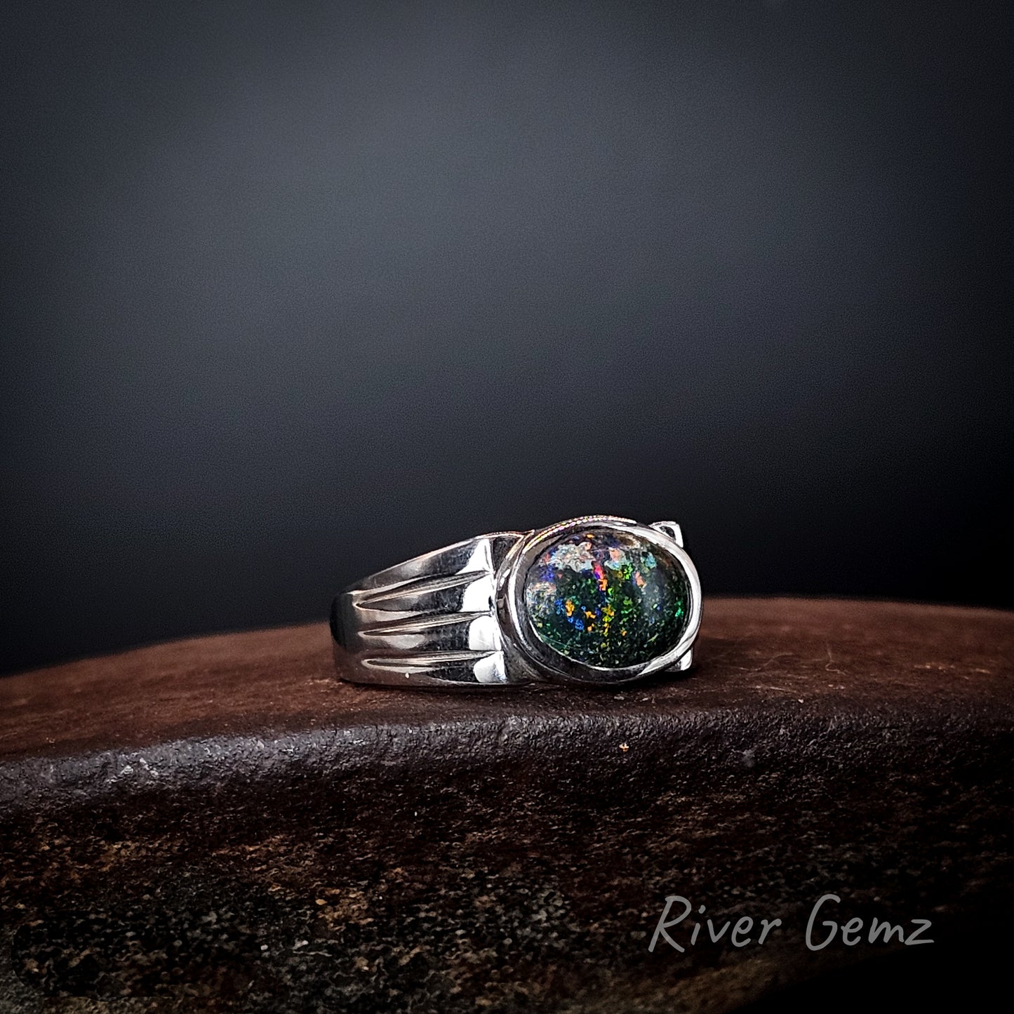 Colourful matrix opal set in sterling silver ring with three tapered lines on the ring's shoulders.