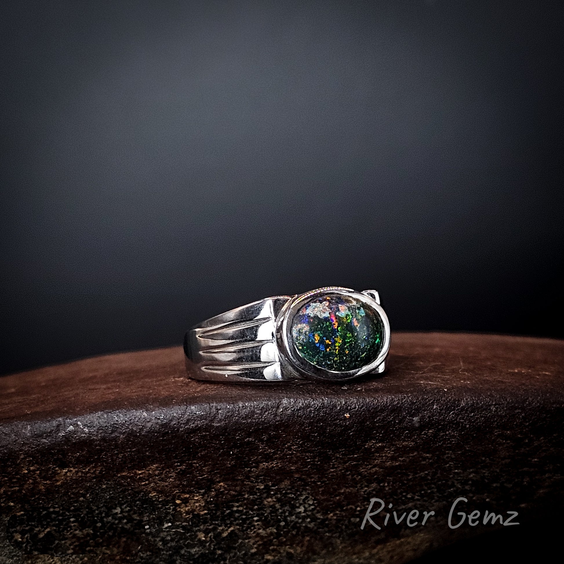 Colourful matrix opal set in sterling silver ring with three tapered lines on the ring's shoulders.