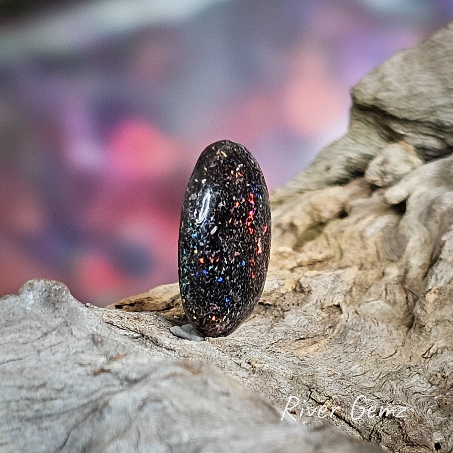 A skewed view of the loose dark multi-coloured opal to show the solid opal thickness.