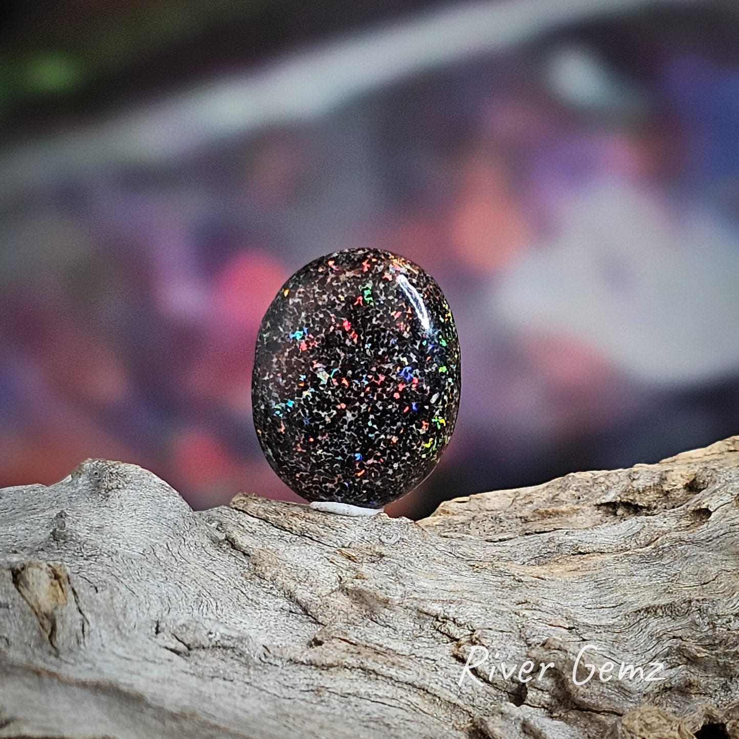 Colourful dark matrix unset opal which is oval shaped.