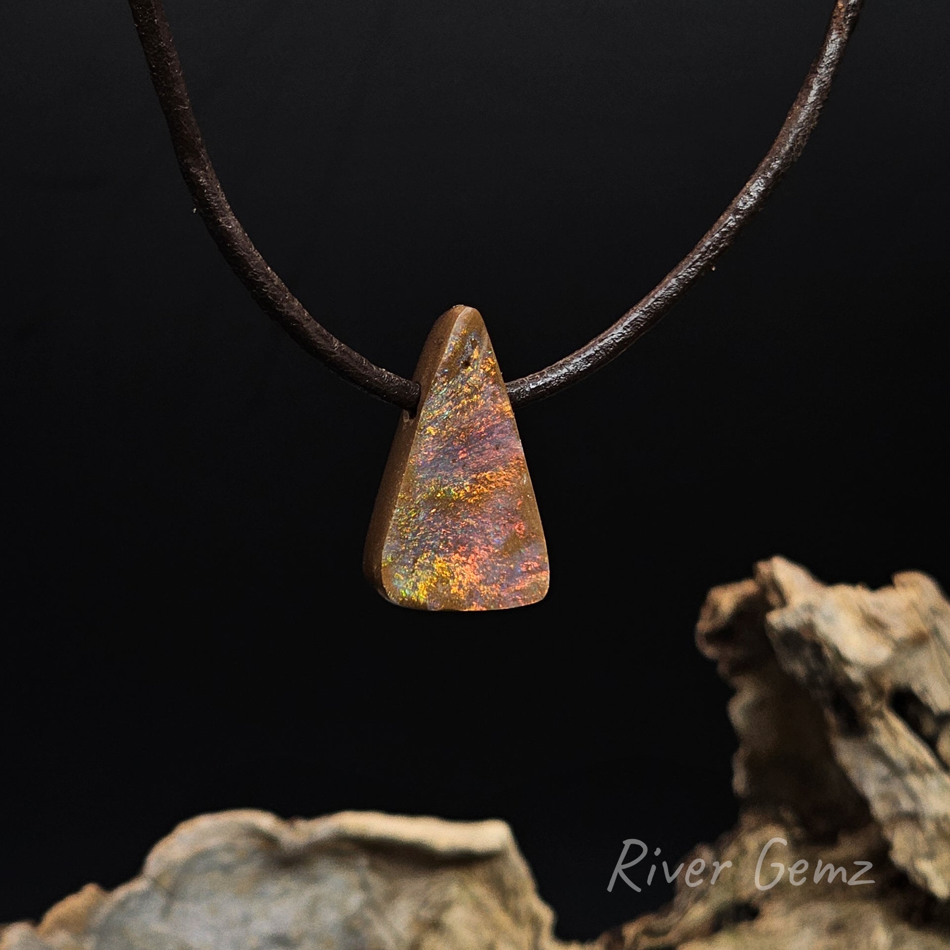 Red, orange, yelow and green fire-like colours on a chocolate base coloured boulder opal side drilled to enable the brown leather cord to pass through.