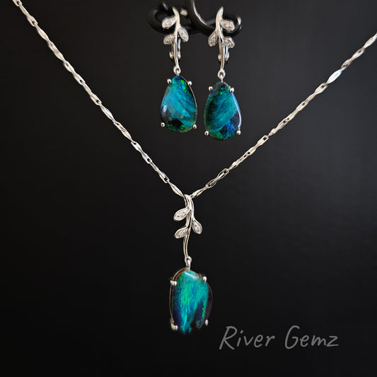 Jewelry set with pendant and earrings featuring blue gemstones on a black background.