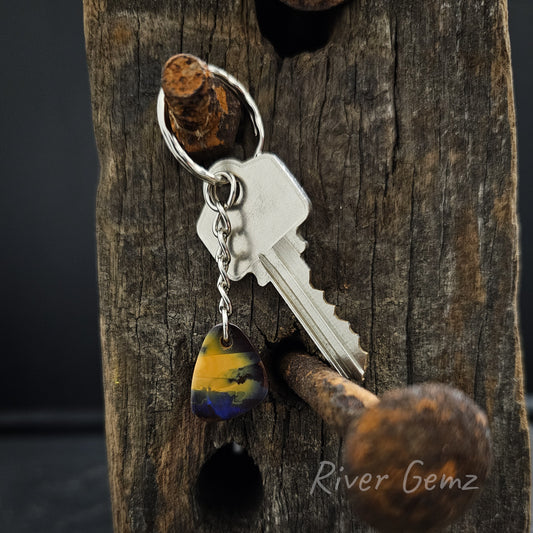 Triangular shaped dark opal with rounded corners hangs on the end of the silver key chain.