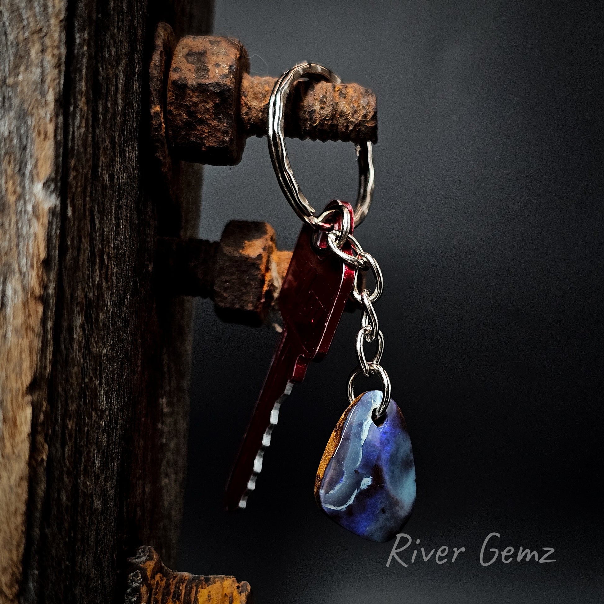 Key ring with a tear drop shaped boulder opal on a dark background, featuring the brand 'River Gemz'.