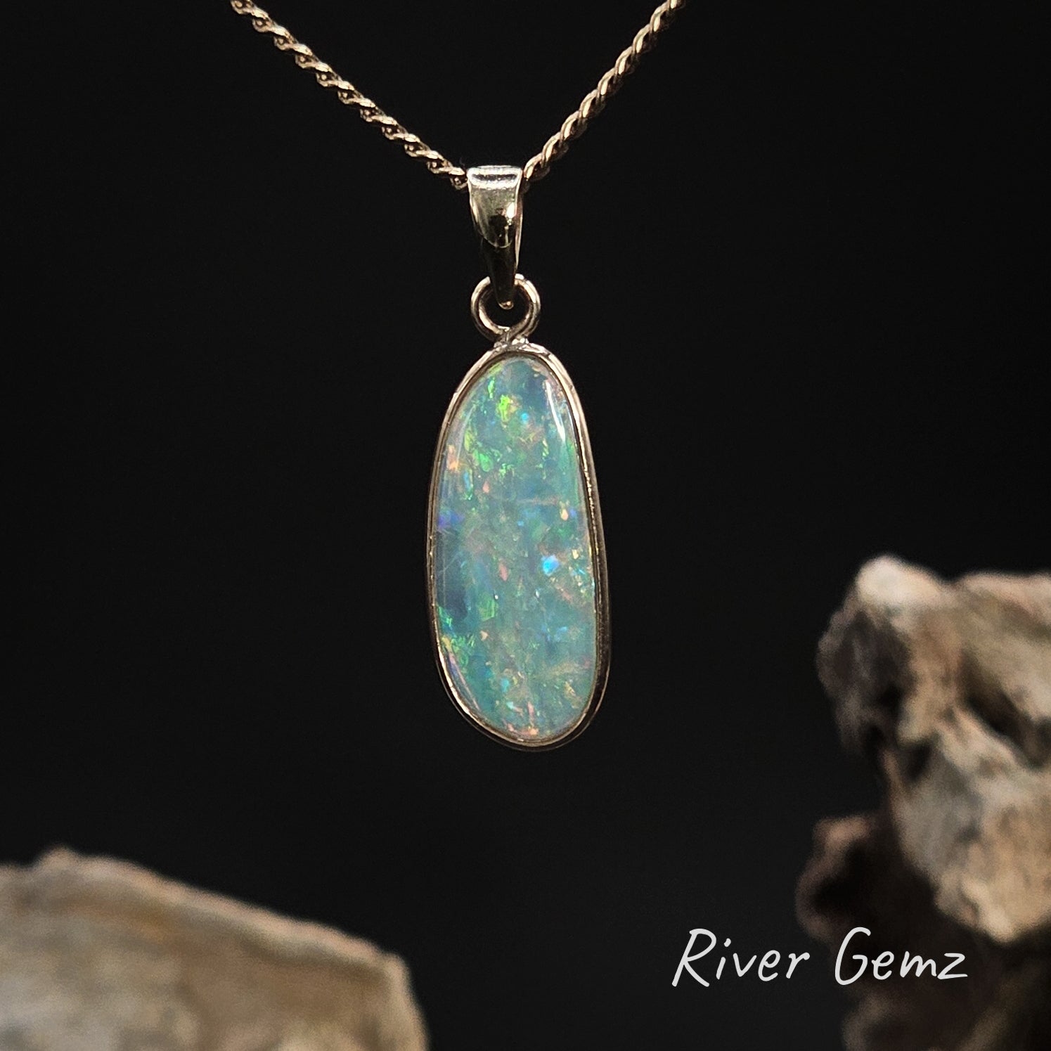 Opal set in a yellow gold necklace on a dark background with 'River Gemz' branding.