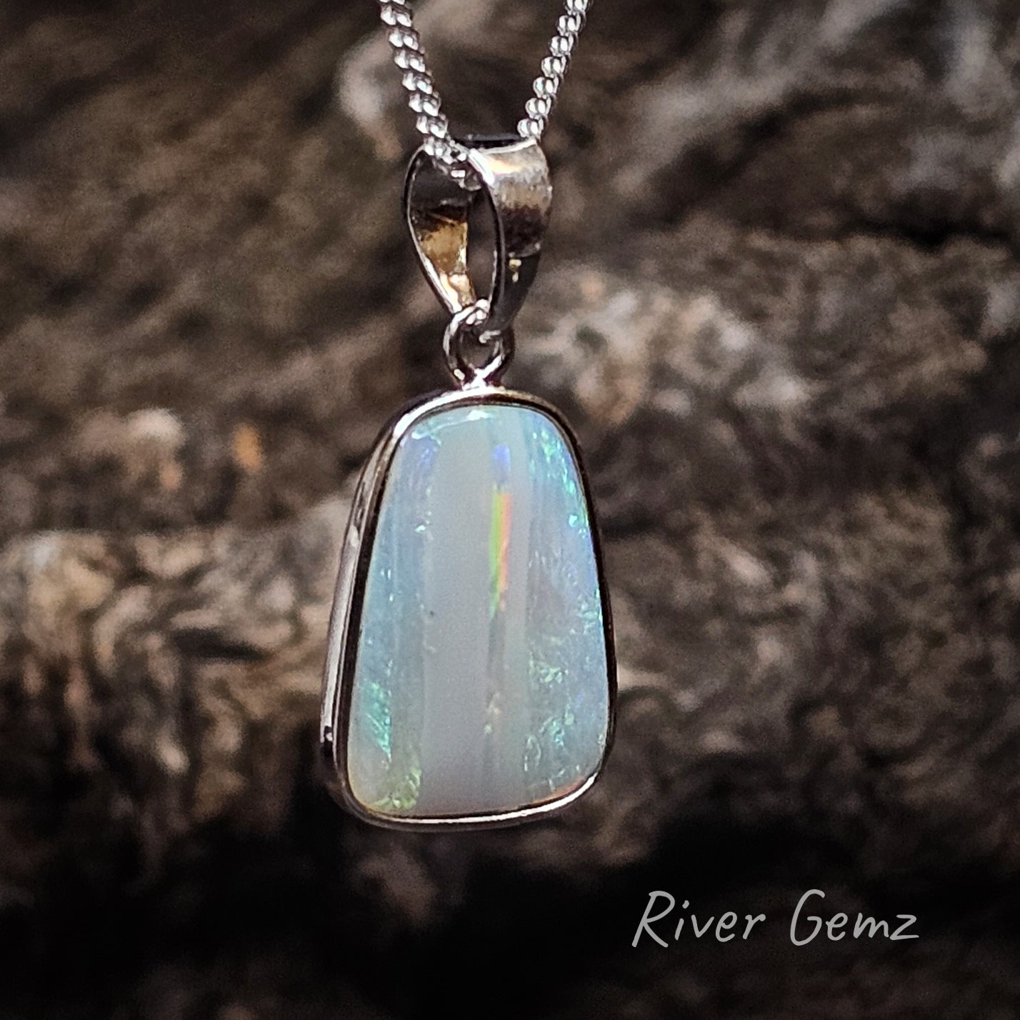 Crystal opal with stripe pattern of blue green and orange splashes in a sterling silver pendant with large bail.