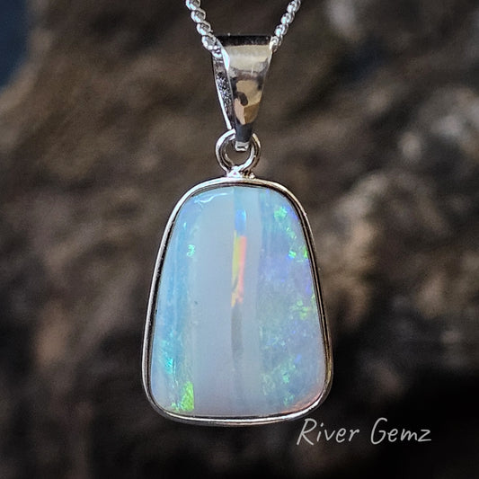 A trapezium shaped light opal with blue and green plus a flash of orange in a silver necklace.