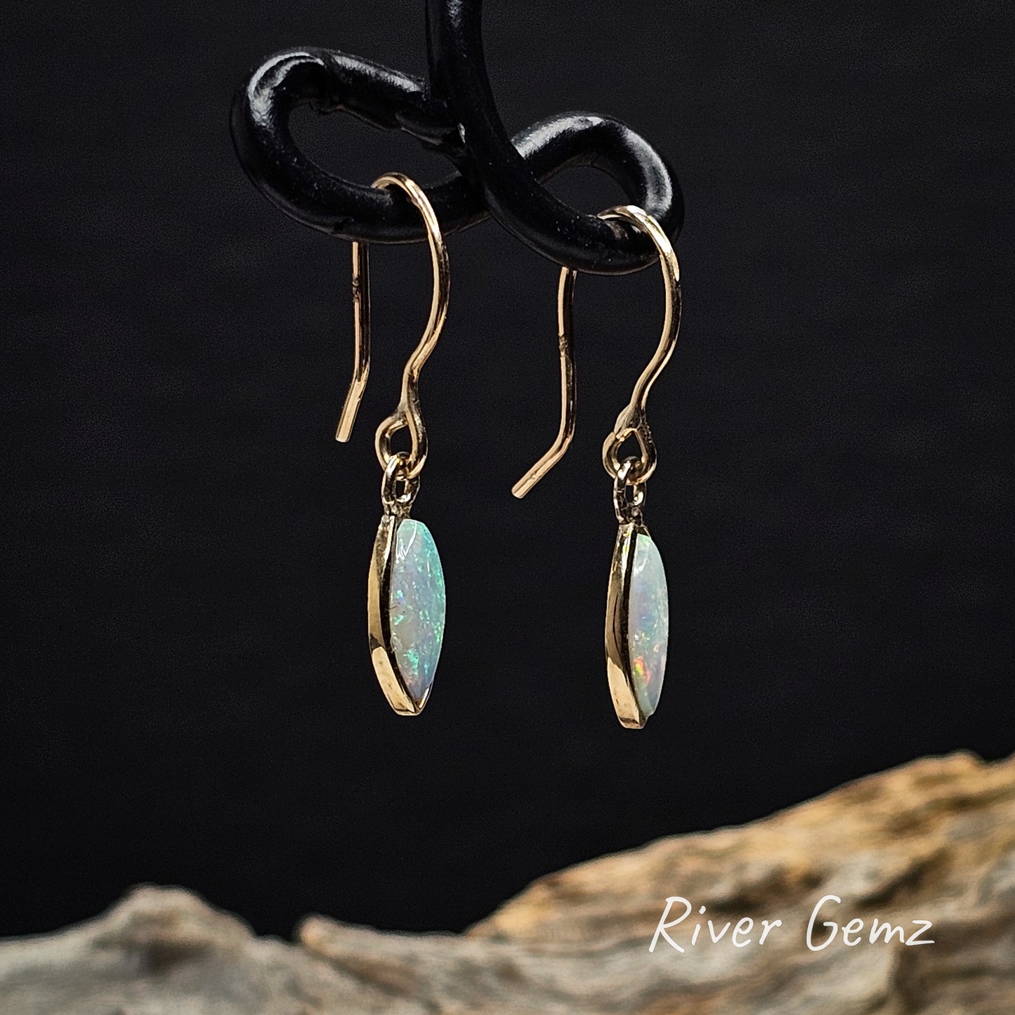 Side view of yellow gold French hooks with light opals against a black background with 'River Gemz' branding.