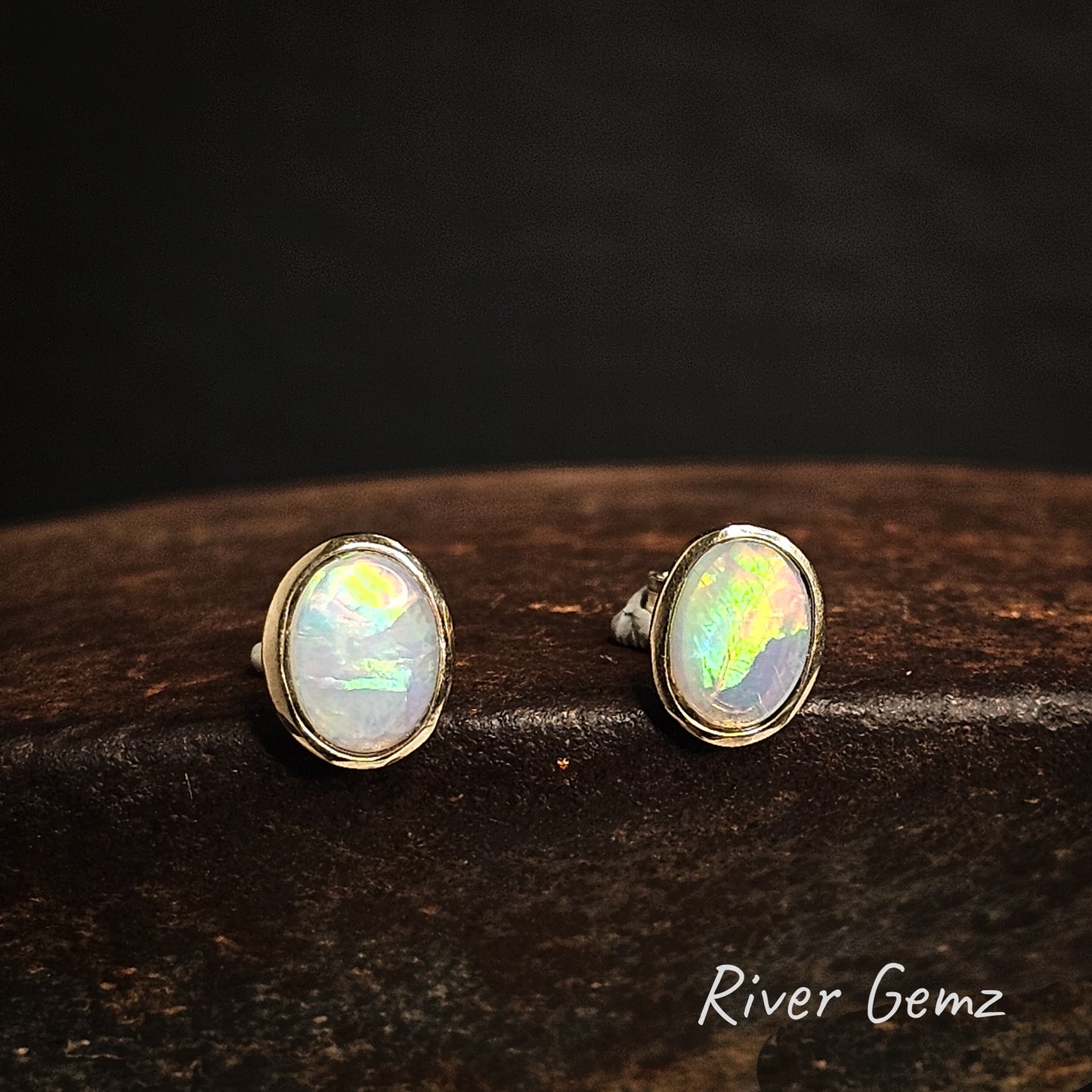 Oval shaped light opals besel set in 14K yellow gold stud earrings.
