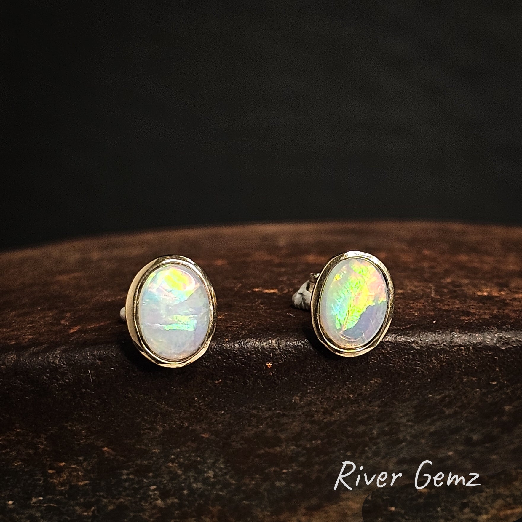 Oval shaped light opals besel set in 14K yellow gold stud earrings.