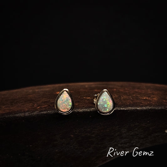 Tear drop shaped multi-coloured light opals set in yellow gold stud earrings.
