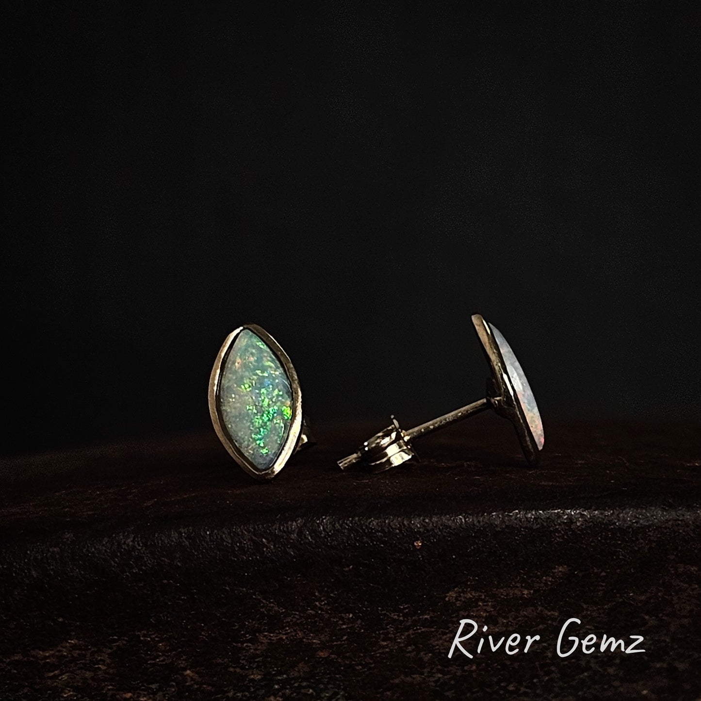 Yellow gold stud earrings with marquee shaped green opals on a dark background with 'River Gemz' branding.
