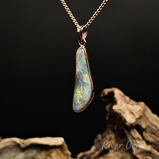 Opal besel set in gold necklace on a dark background with 'River Genz' branding.