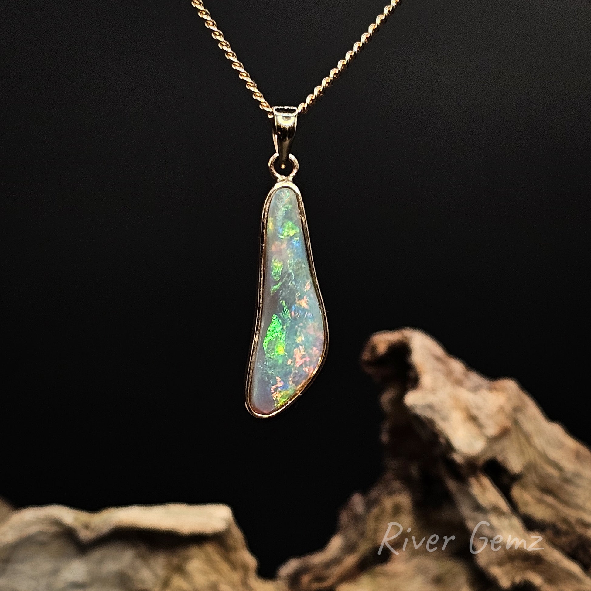 Opal pendant on a gold chain with a dark background