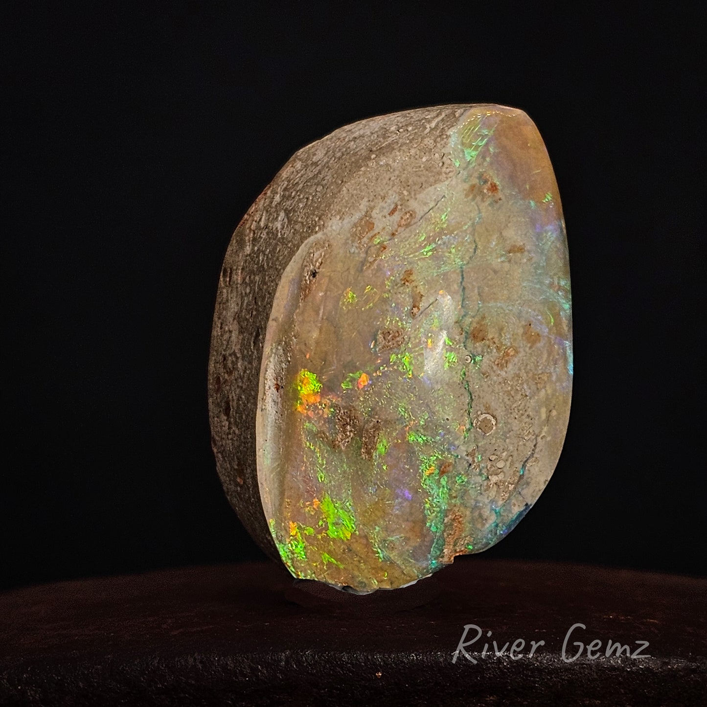 Polished opal stone with multicolored play of light on a black background