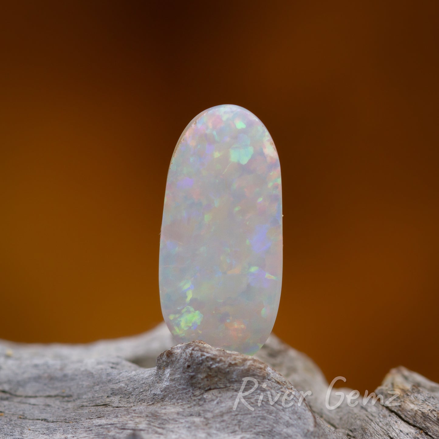 Oblong shaped white loose opal shown standing upright.