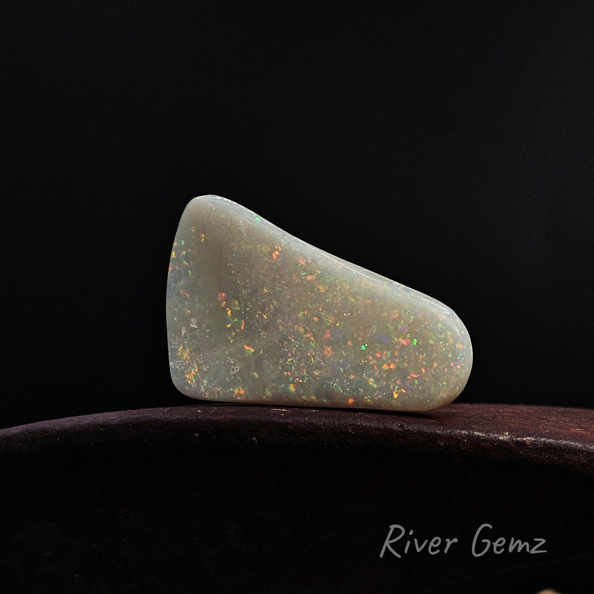 Loose multi-colour opal shown lying horizontally on its edge.