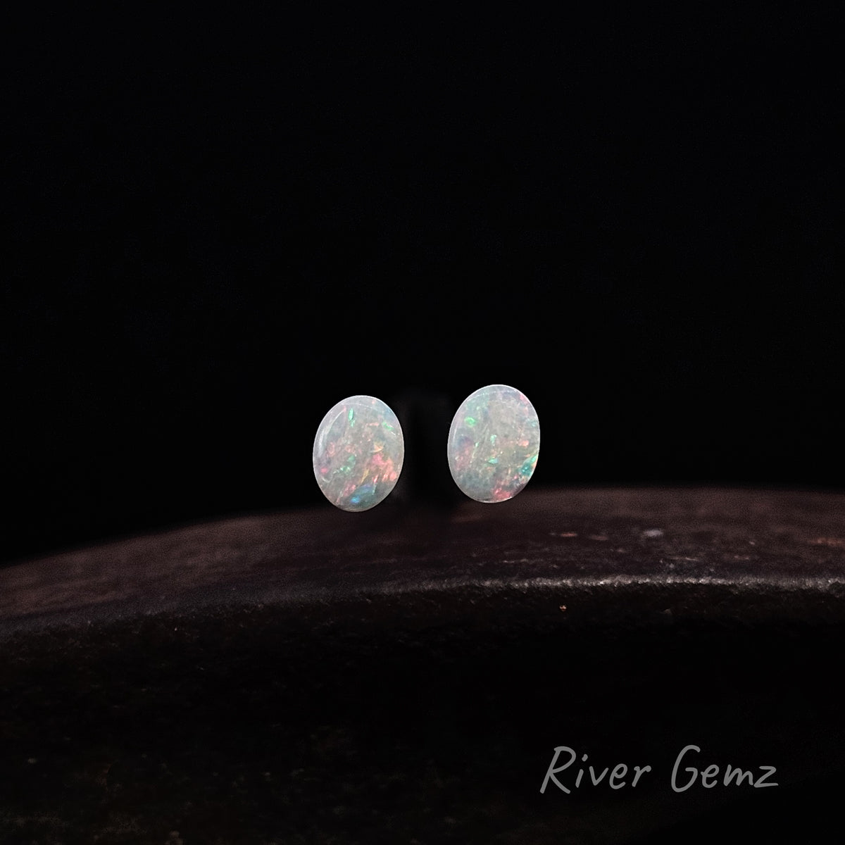 Oval shaped pair of light opals with orange, blue and green colours. "River Gemz" watermark is in the bottom right hand corner.
