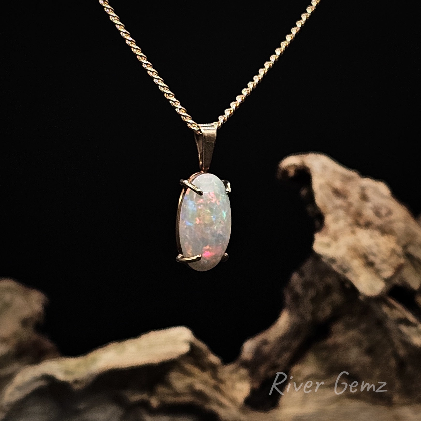 Multi-coloured white opal set in yellow gold pendant on a dark background with 'River Gemz' branding.
