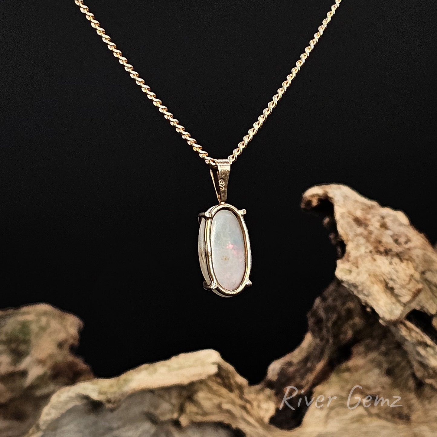 Rear view of necklace shows the light base tone of the white opal on a gold chain with a dark background and 'River Gemz' branding.