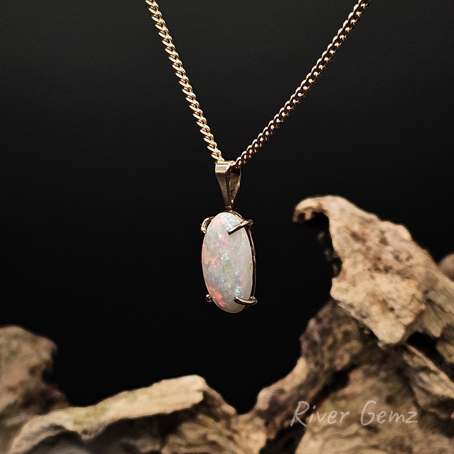 Oval shaped light opal on a gold chain with a dark background