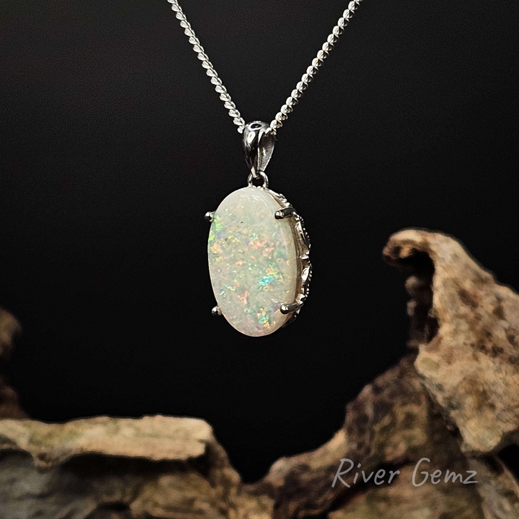 White opal claw set in silver necklace on a dark background with 'River Gemz' branding.