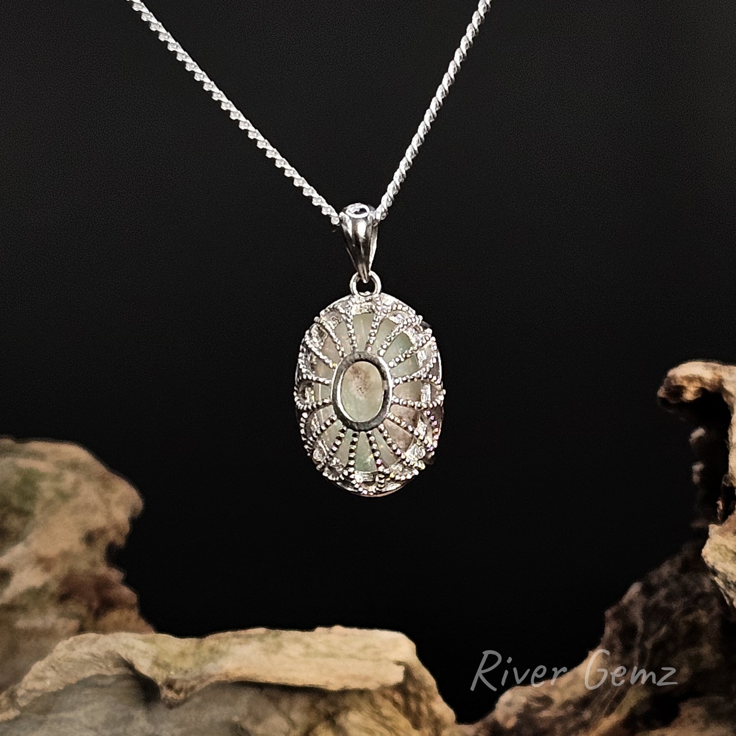 Rear view of the pendant shows the lattice type of setting enclosing the back of the white opal on a dark background with 'River Gemz' branding.