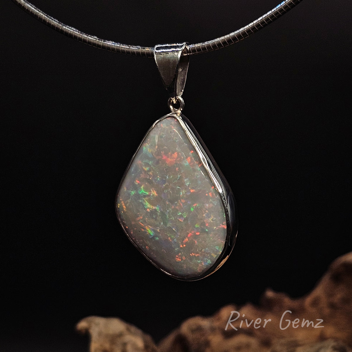 Large multi-colour white opal besel set in silver necklace against a black background and 'River Gemz' water mark in bottom right hand corner.