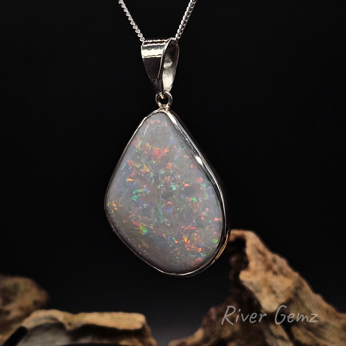 Light opal with orange, red, blue and green besel set in silver necklace.