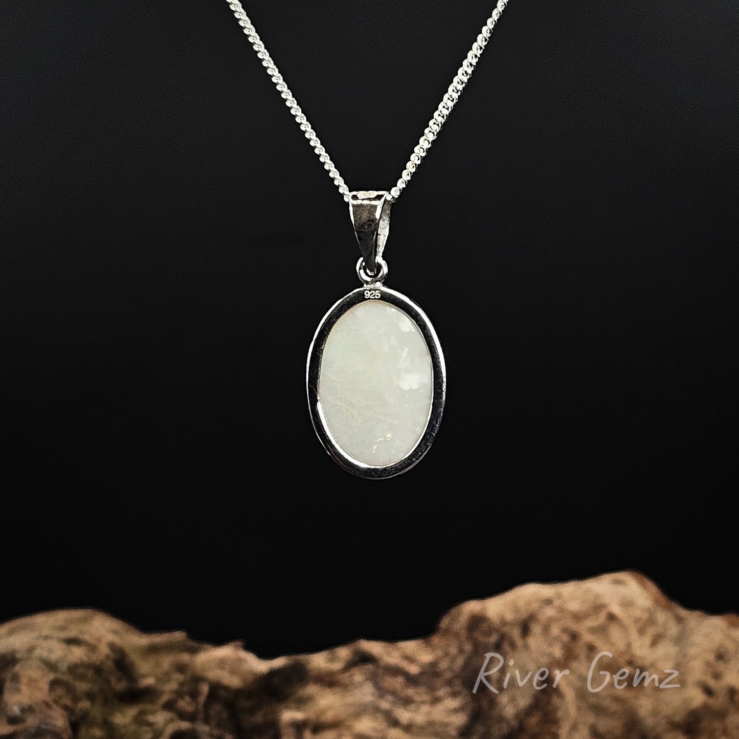 Rear view of silver pendant shows the light base tone of the white opal set in it. The 925 hall mark is shown on the rim of setting to indicate sterling silver.