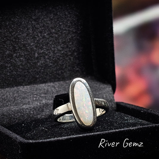 Elongated oval shaped light opal fully besel set in silver ring.