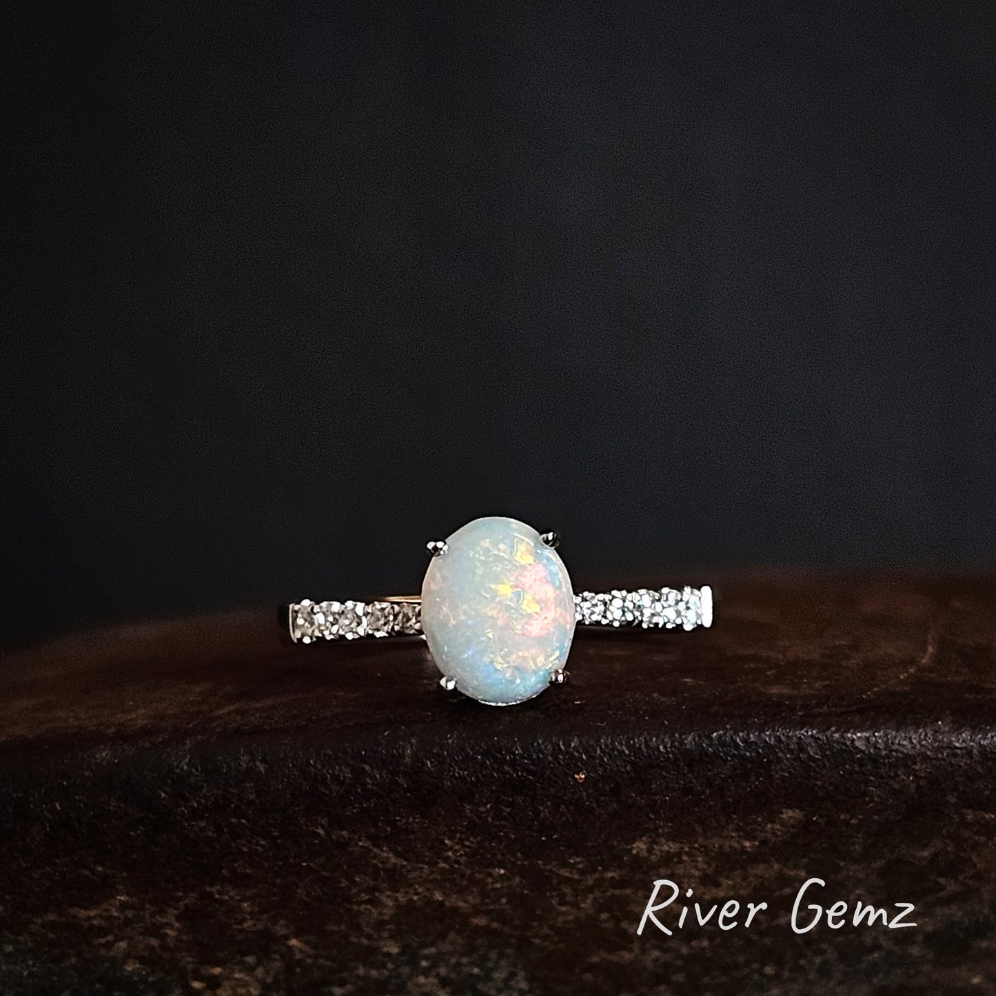 Opal ring with white topaz on a dark background, branded 'River Gemz'.