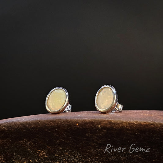 Pair of silver earrings with yellow gemstones on a dark background, branded 'River Gemz'.