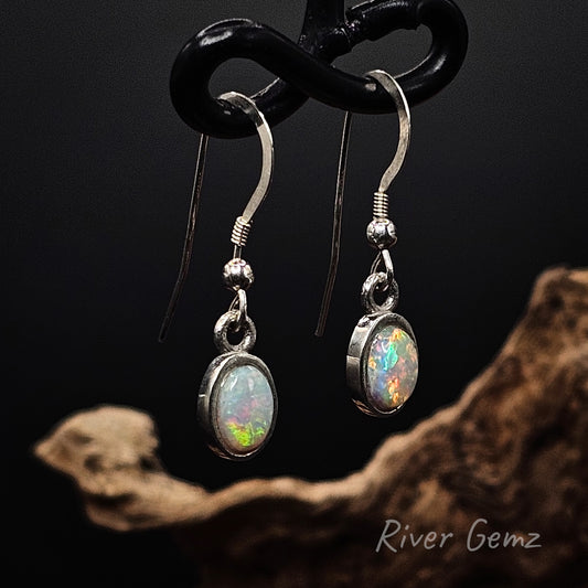 HIgh domed multi-coloured white opals besel set in silver French hooks.