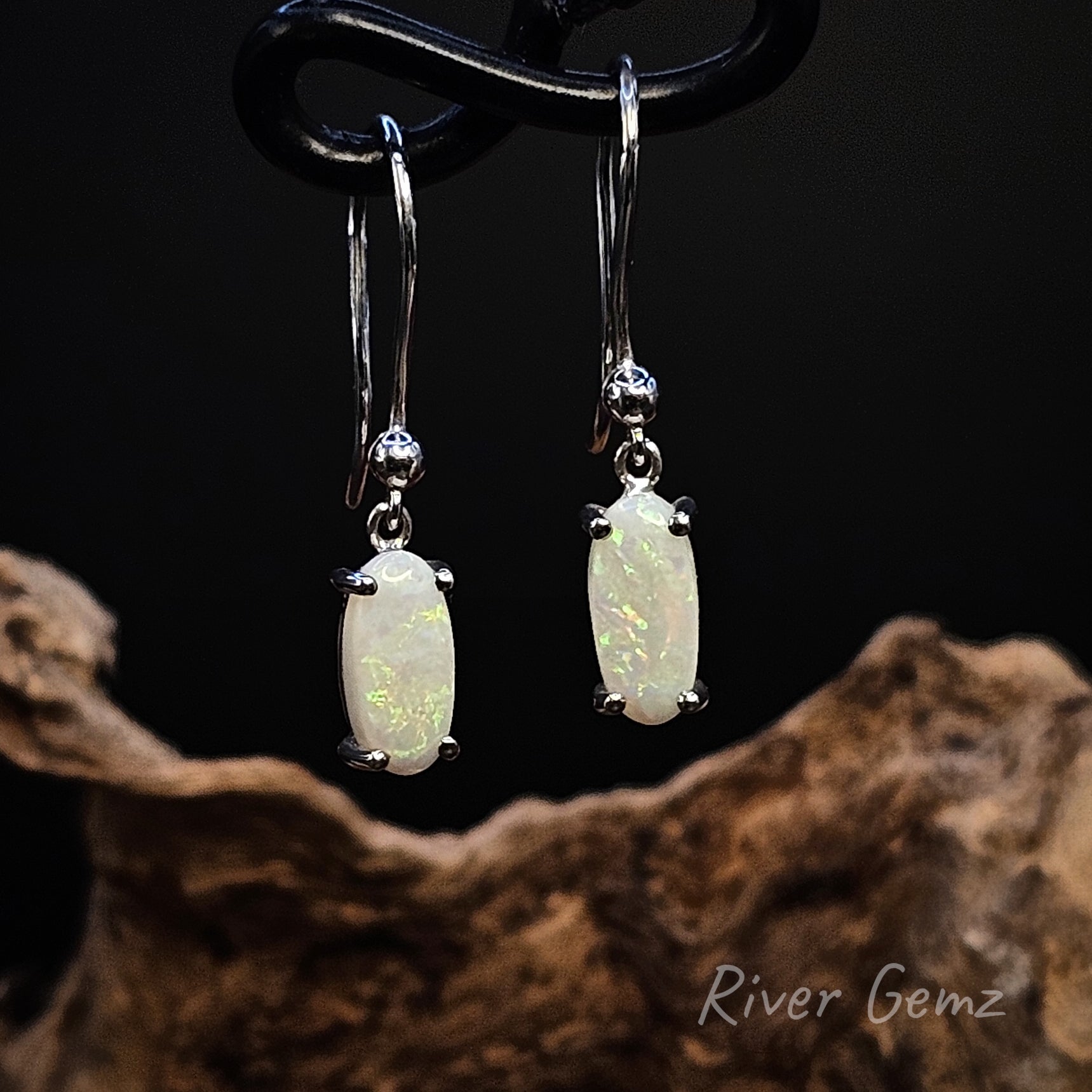 White opal in sterling silver earrings on a dark background with 'River Gemz' branding.