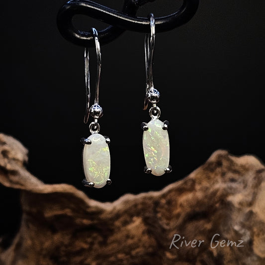 White opal in sterling silver earrings on a dark background with 'River Gemz' branding.