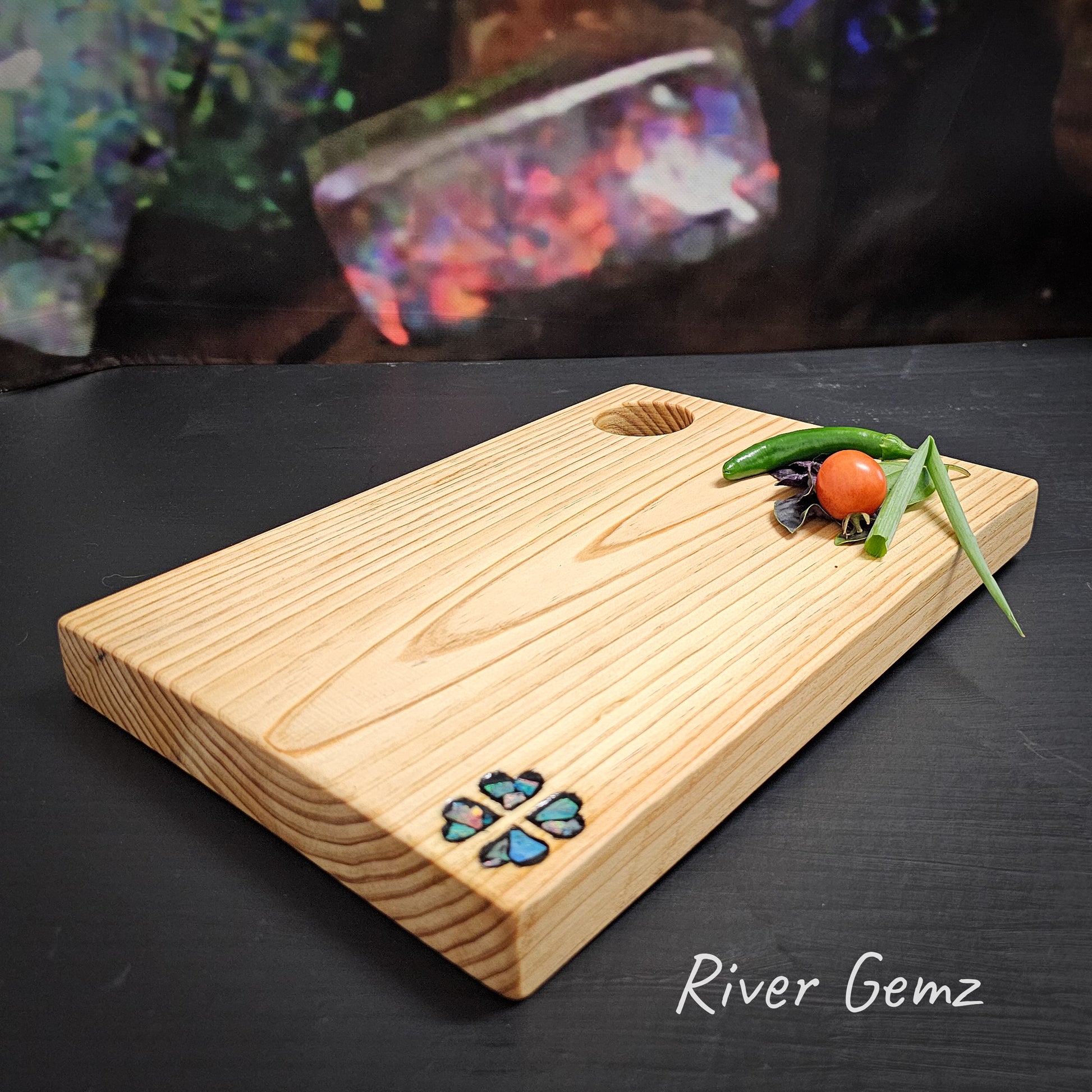 Small wooden charcuterie board with four love hearts in an multi-coloured opal mosaic.