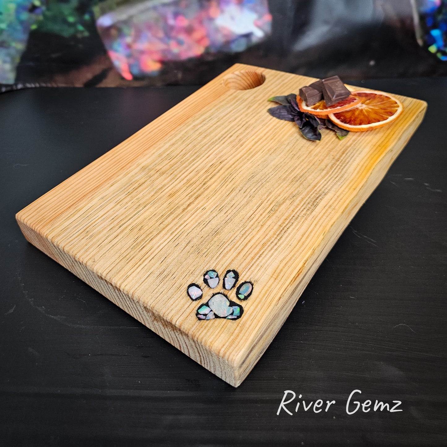 Multi-coloured opal slices used to create an pawprint mosaic showcased in the light grain wooden charcuterie board.