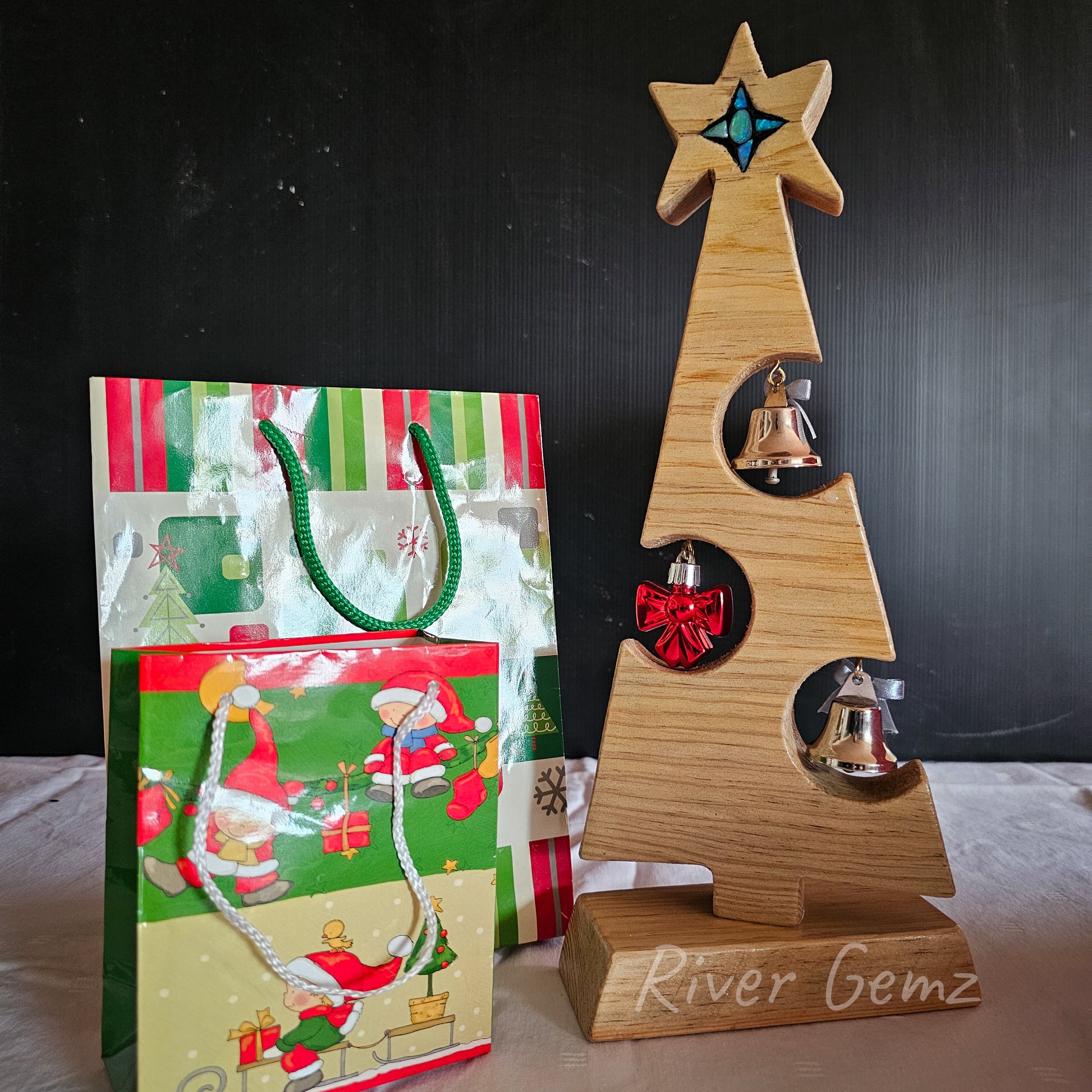 A different opal mosaic star features on this side of the wooden small Christmas tree. The partial circles cut out of the sides of the wooden tree have Christmas ornaments hanging within them which are visible from each side.