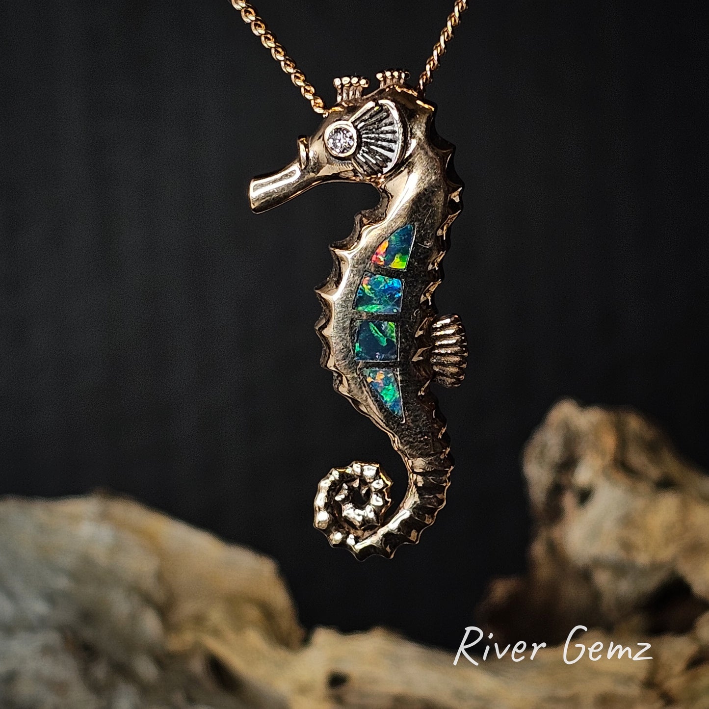 Gold seahorse pendant with opal inset on a dark background, featuring 'River Gemz' branding.