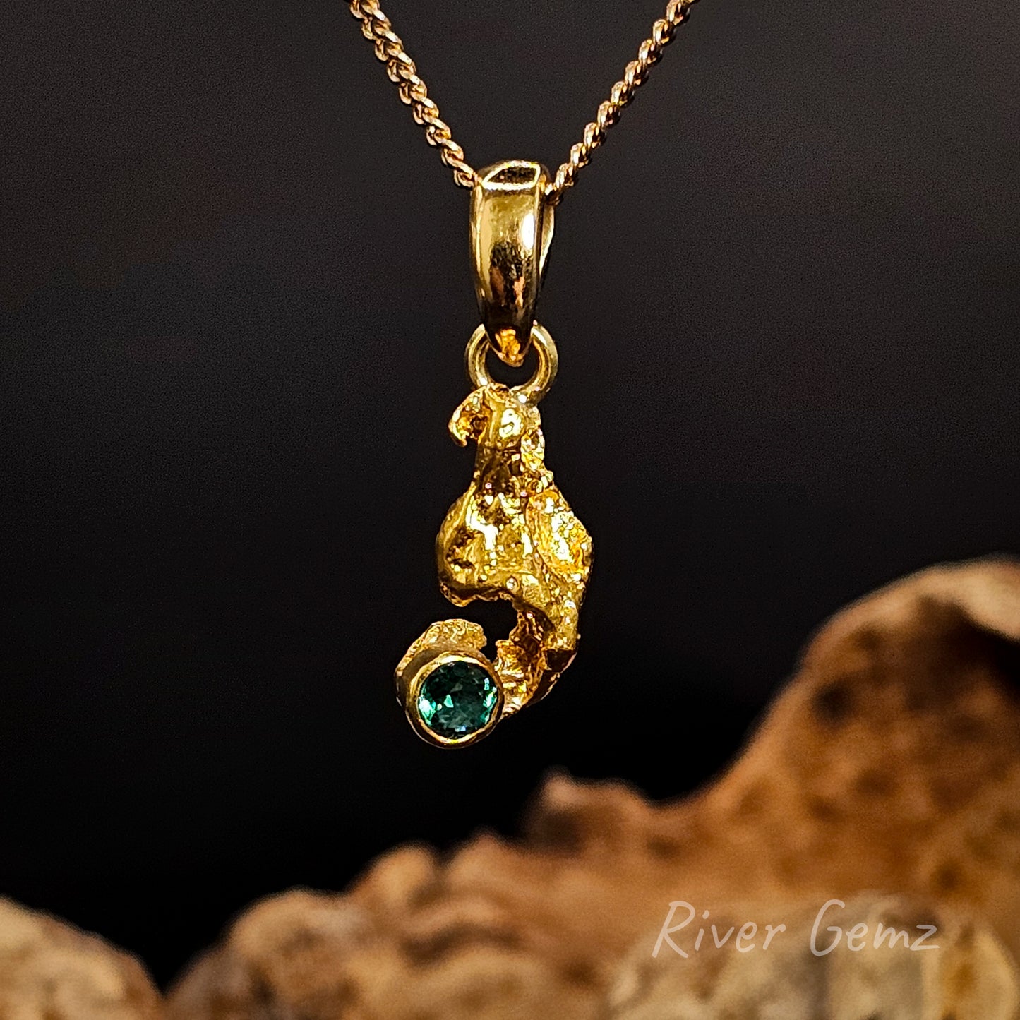 Gold nugget with emerald set in yellow gold pendant.
