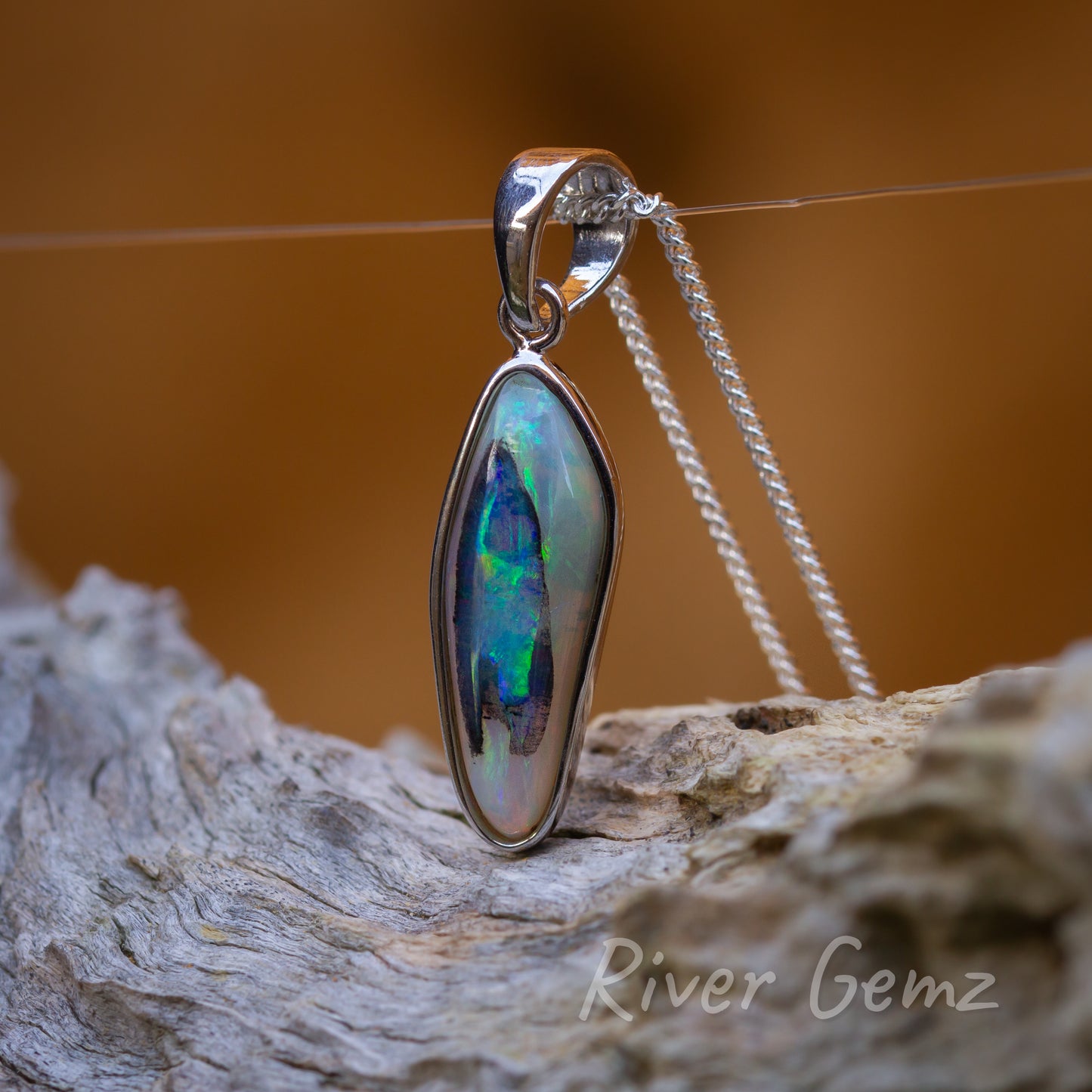 Unusual shape and colouring in this opal. Large tapered bail half the height of the opal completes the setting.