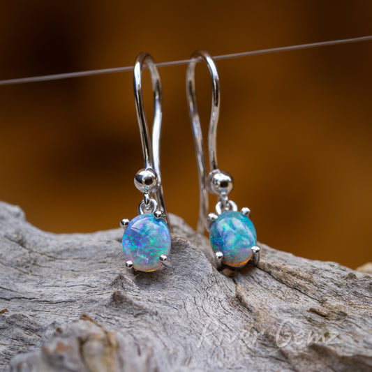 Four claws secure the oval shaped opals in each earring.  A small ball on the extra long hook is an added feature. Blue greens of the ocean in each opal captivate.