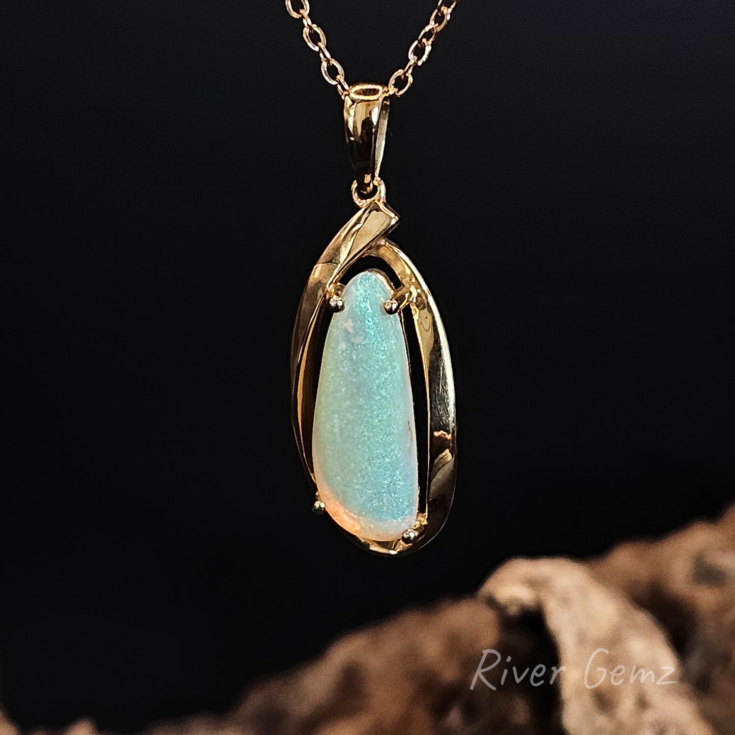 Gold pendant with a green crystal opal on a dark background