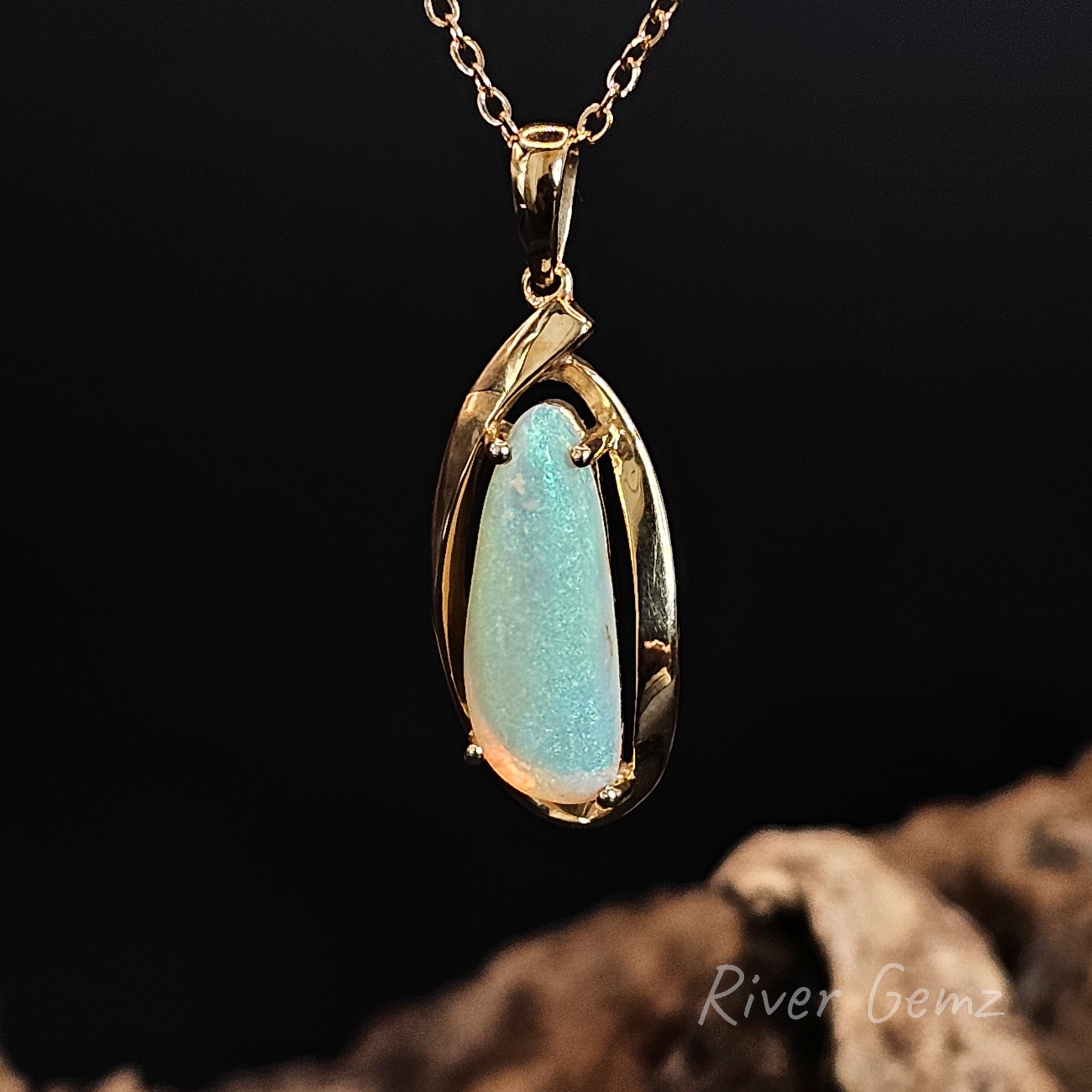Gold pendant with a green crystal opal on a dark background