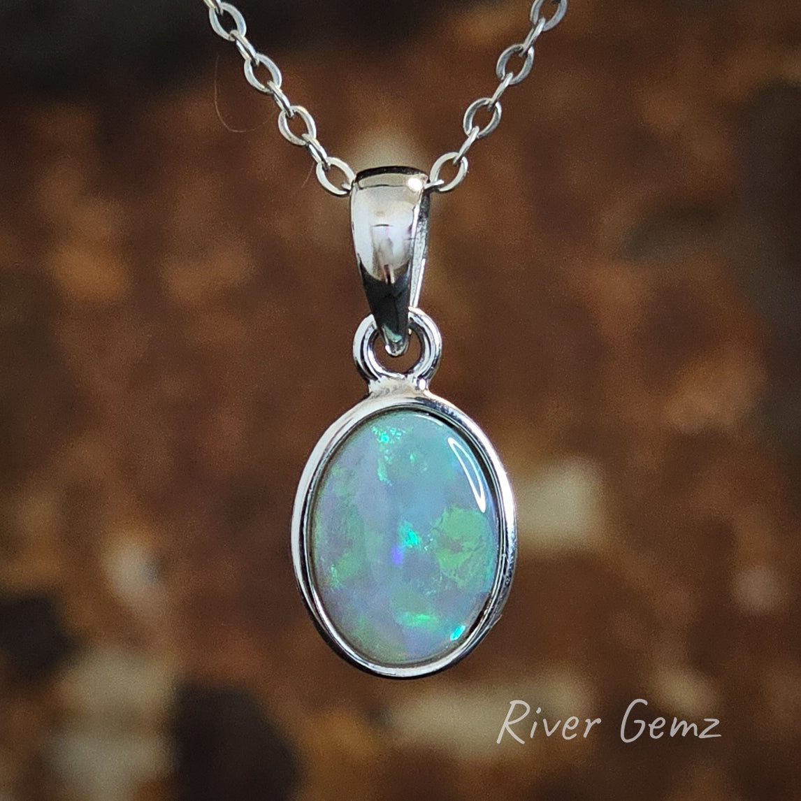 Oval shaped blue and green light opal in silver necklace.